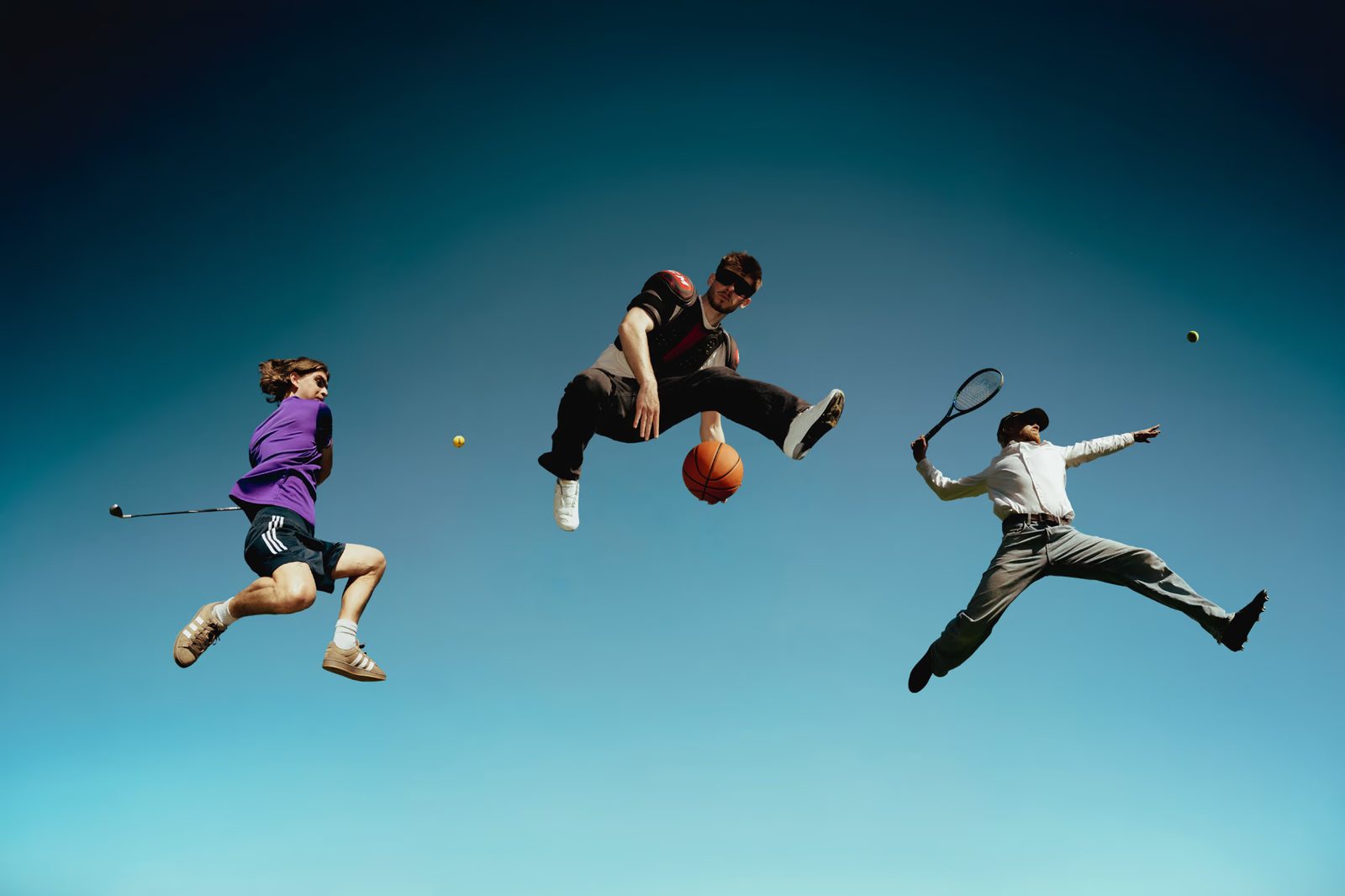 Drie sporters springen hoog in de lucht met een golfclub, een basketbal en een tennisracket tegen een blauwe hemel